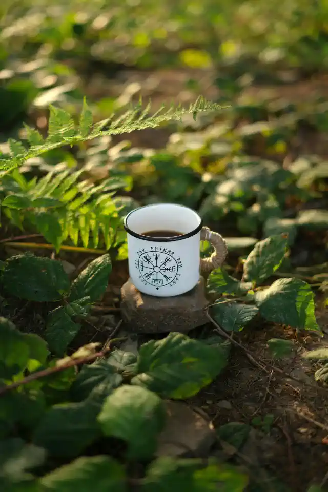 Personalizēti suvenīri - zālē nolikta balta krūzīte ar melnu ornamentu