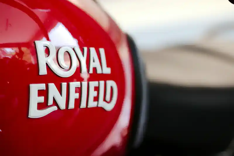 Logo dizaina izstrāde - balti, savīti burti uz sarkanas, spīdīgas virsmas